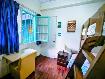 a bedroom with a bed and a desk and a window at La Casona Azul in Lima