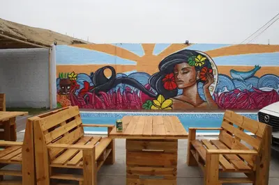a table and chairs in front of a mural at Surfari Punta Rocas in Punta Negra
