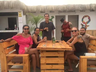 a group of people sitting around a wooden table at Surfari Punta Rocas in Punta Negra