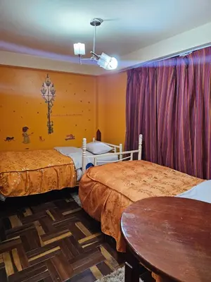 a hotel room with two beds and a table at Hostal Casa Del Inka in Cusco