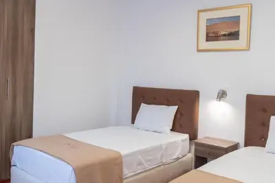 a bedroom with two beds with white sheets and a lamp at Hostal Los Frayles in Paracas