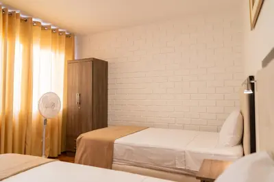 a bedroom with two beds and a fan at Hostal Los Frayles in Paracas