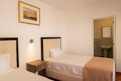 a hotel room with two beds and a sink at Hostal Los Frayles in Paracas
