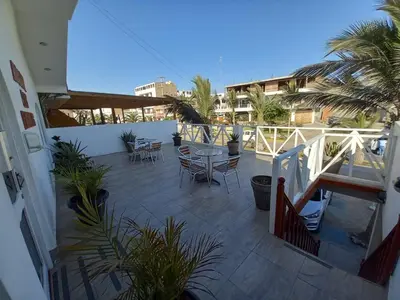 a patio with a table and chairs on a balcony at Hostal Los Frayles in Paracas
