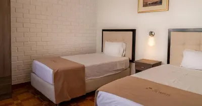 two beds in a small room with white walls at Hostal Los Frayles in Paracas