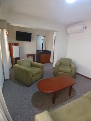 a living room with two chairs and a table and a couch at Hotel Melodia in Lima