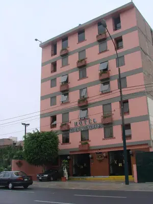 a pink building with a sign for a hotel at Hotel Melodia in Lima
