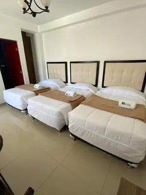 a group of four beds in a room at Hotel Residencial Los Frayles in Paracas
