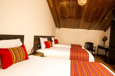 a bedroom with two beds with red and white at Hotel San Pedro Plaza in Cusco