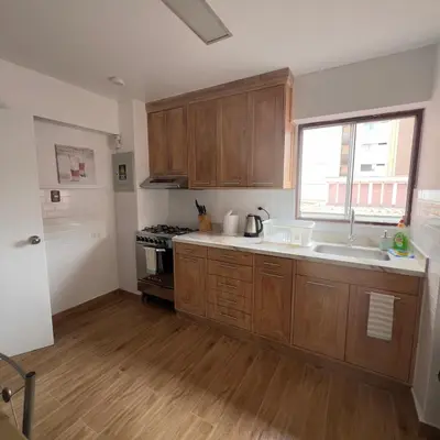 a kitchen with wooden cabinets and a sink and a window at Maywa at Central Miraflores in Lima