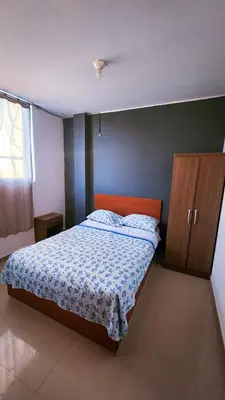 a bedroom with a bed and a wooden cabinet at Hospedaje Villa Del Sol in Ica