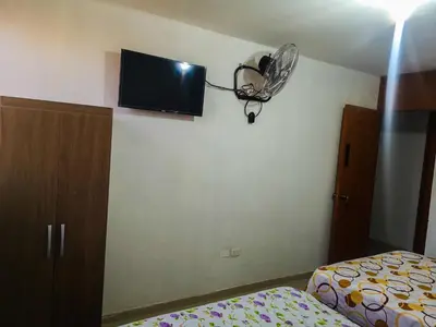 a bedroom with a bed and a fan on the wall at Hospedaje Villa Del Sol in Ica