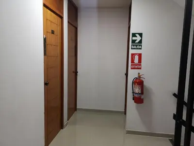 a hallway with a fire extinguisher sign on the wall at Hospedaje Villa Del Sol in Ica