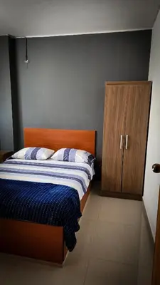 a bedroom with a bed and a wooden cabinet at Hospedaje Villa Del Sol in Ica