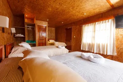 a bedroom with three beds and a window at Hotel Heidinger in Oxapampa