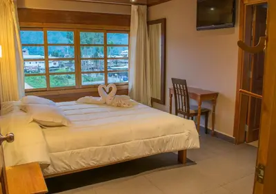a bedroom with a bed and a window and a desk at Hotel Heidinger in Oxapampa