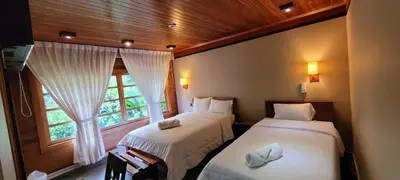 two beds in a room with a window at Hotel Heidinger in Oxapampa