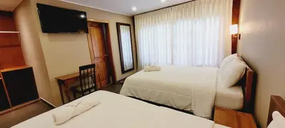 a hotel room with two beds and a flat screen tv at Hotel Heidinger in Oxapampa
