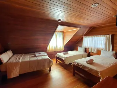 a bedroom with two beds and a wooden ceiling at Hotel Heidinger in Oxapampa