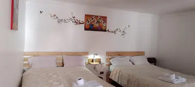 a bedroom with two beds and a painting on the wall at Casa Anais y Nicolas económico in Cusco