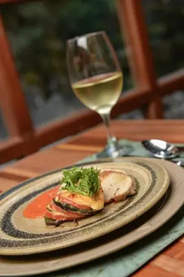 a plate of food and a glass of white wine at Casa del Sol Machupicchu in Machu Picchu