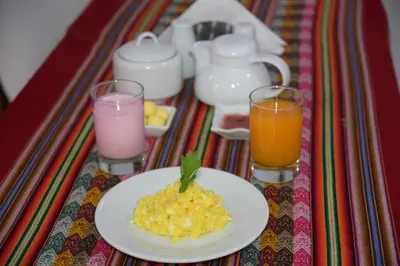 a table with a plate of food and two glasses of juice at MAPILAND- Hotel Boutique in Machu Picchu