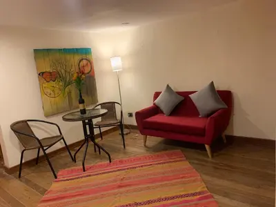 a living room with a red couch and a table at Gaia House Hostel in Cusco