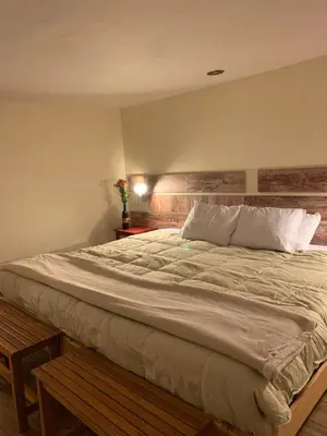 a bedroom with a large bed with a wooden headboard at Gaia House Hostel in Cusco
