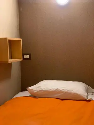 a bed with an orange sheet and a white pillow at Gaia House Hostel in Cusco
