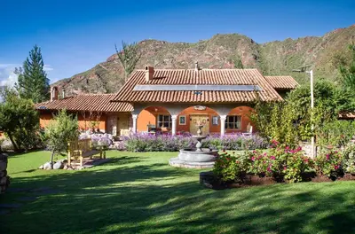 a house with a fountain in front of a yard at VILLA APU CHICON (Apu Wasi & Inti Wasi) in Urubamba