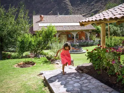 a little girl in a red dress walking on a path at VILLA APU CHICON (Apu Wasi & Inti Wasi) in Urubamba