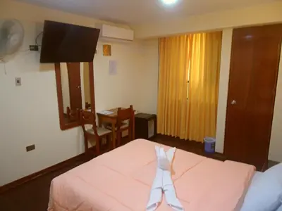 a bedroom with a bed and a desk and a television at Hotel Panamericano in Lima