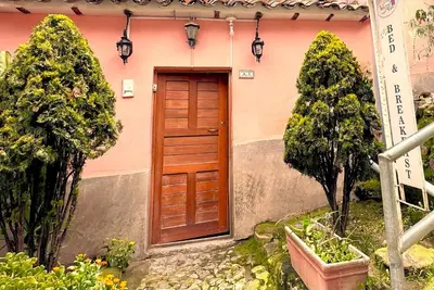 a wooden door on a pink house with two trees at Welcome Cusco Hostel in Cusco