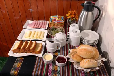 a table with plates of food and bread and coffee at Welcome Cusco Hostel in Cusco