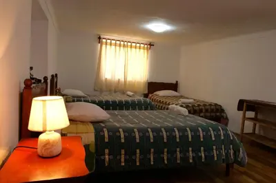 a room with two beds and a lamp on a table at Welcome Cusco Hostel in Cusco