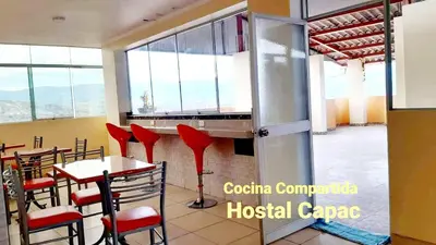 a restaurant with red chairs and tables and windows at Hostal Capac in Ayacucho