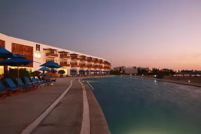 a swimming pool with chairs and umbrellas next to a building at San Agustin Paracas in Paracas