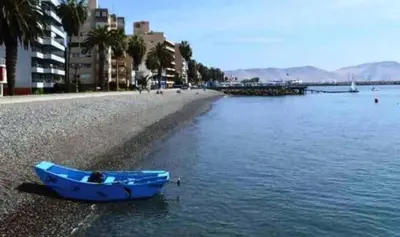 a blue boat sitting on the shore of a body of water at Jirón Tarapacá 398, La Punta - Callao in Lima