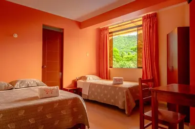 a hotel room with two beds and a window at Refugio Hotel in San Ramón