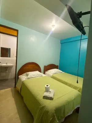 a room with two beds with a light on the wall at Hotel Villa Santa Ana in Quillabamba