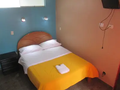 a bedroom with a large bed with a wooden headboard at Hotel Villa Santa Ana in Quillabamba