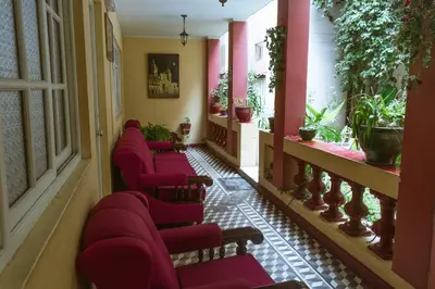 a row of red chairs in a hallway with plants at Hospedaje Zaragoza in Ayacucho