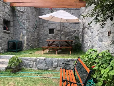 a wooden bench with an umbrella next to a table at Casa Campo Machu Picchu - Club Los Girasoles, Chaclacayo in Chaclacayo