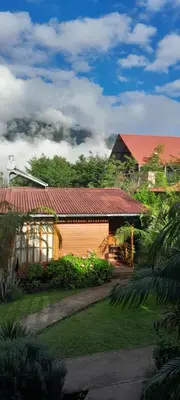 a yellow house with a red roof in a yard at Chontaqui Eco-Lodge in Oxapampa