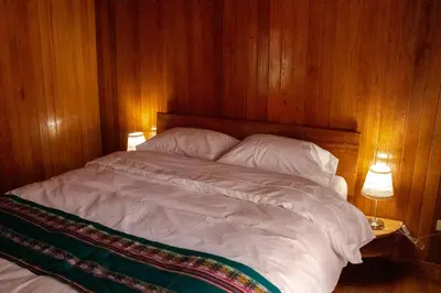 a bedroom with a bed with wooden walls and two lamps at Chontaqui Eco-Lodge in Oxapampa