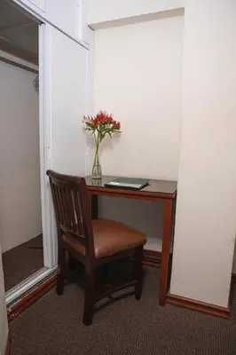 a desk with a chair and a vase of flowers on it at Hotel Ferrua in Lima