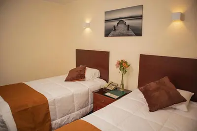 a hotel room with two beds and a phone at Hotel Ferrua in Lima