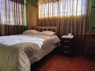 a bedroom with a bed and a window with curtains at Hospedaje Manchego's in Huancayo