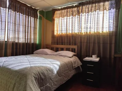 a bedroom with a bed and a window with curtains at Hospedaje Manchego's in Huancayo