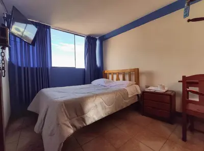 a bedroom with a bed and a large window at Hospedaje Manchego's in Huancayo